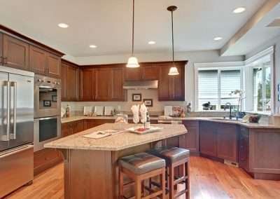 A spacious modern kitchen with dark wood cabinets, granite countertops, and stainless steel appliances.