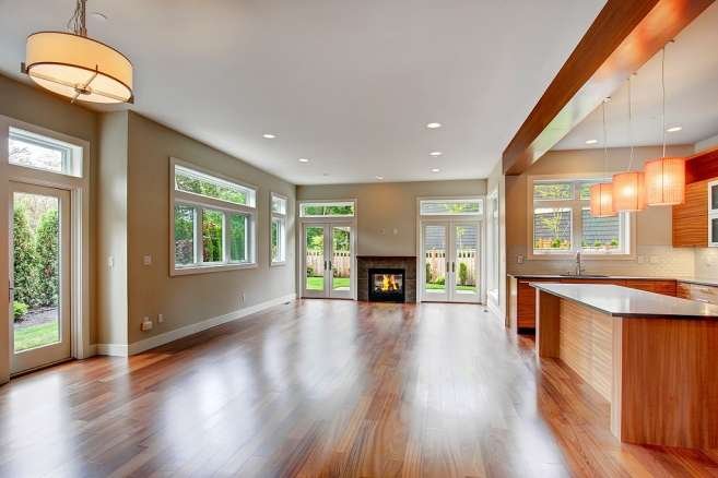 A spacious living area with hardwood floors, a built-in fireplace, and large windows overlooking the garden.