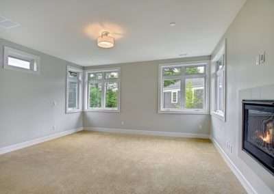 A large master bedroom featuring a built-in fireplace, multiple windows, and soft carpeting, providing comfort and warmth.