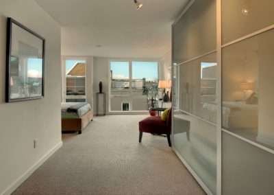 A stylish bedroom with modern decor, featuring a bed, a seating area, and sliding doors leading to an outdoor balcony.