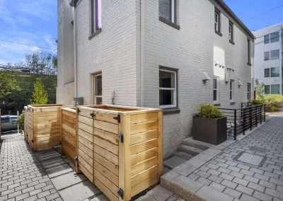 A back alley view showing a modernized pathway, fencing, and adjacent buildings