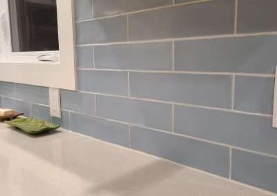 A close-up of a kitchen backsplash with light blue tiles and a light countertop.
