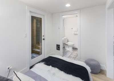 A bedroom with a cozy bed and direct access to a bathroom with patterned tiles.
