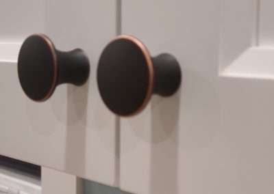 A stylish close-up of black knobs on pristine white kitchen cabinets, adding a touch of elegance to the kitchen decor.