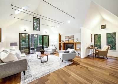 A bright living area with modern furniture, high ceilings, and a fireplace, connected to a cozy reading nook.