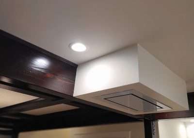 Recessed lighting and a sophisticated ceiling vent highlight the modern design elements of this kitchen.