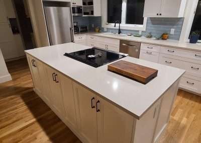 A central kitchen island with an integrated cooktop, surrounded by white cabinets and modern stainless steel appliances.