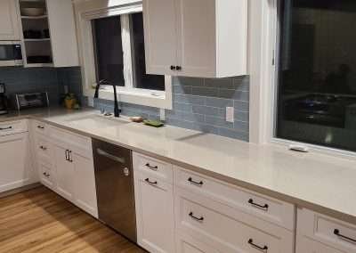 A clean, modern kitchen with white cabinetry and stainless steel appliances.