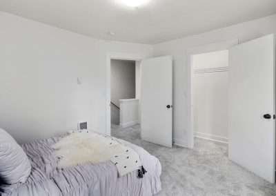 A comfortable bedroom with a bed, bedside tables, and large windows overlooking greenery.