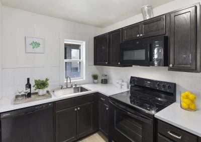 A compact kitchen layout with black cabinetry, white countertops, and modern appliances