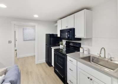 A modern open-plan living area with a cozy sofa, fireplace, dining table, and kitchen in the background.