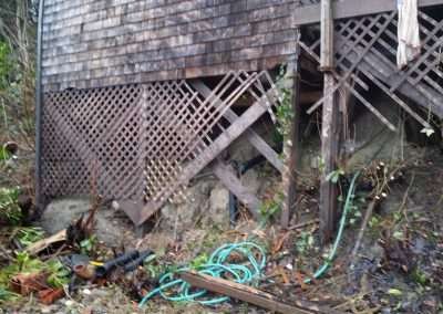 A house with a damaged foundation and broken lattice
