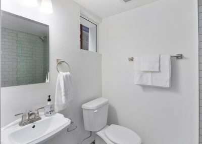 A clean, white bathroom with a glass shower, toilet, and a small sink.