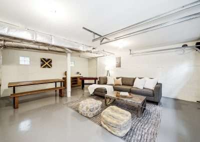 Remodeling services Seattle: Spacious basement recreation room transformation with modern finishes, sectional sofa, and ample lighting.