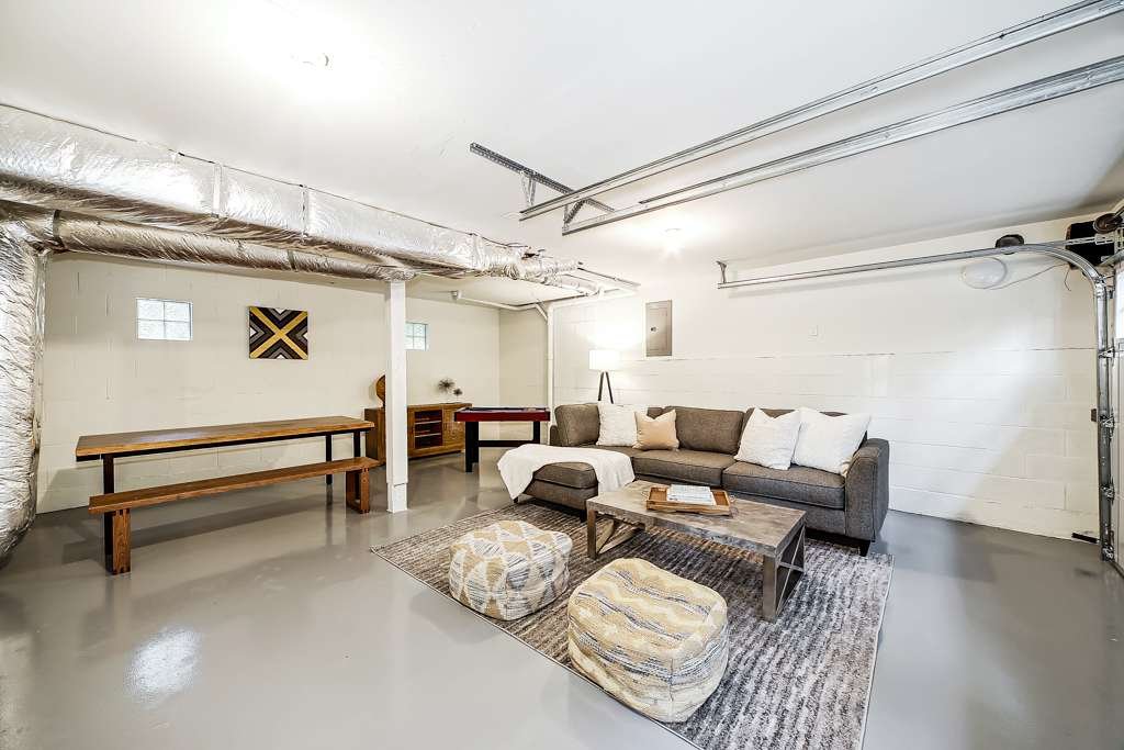 Remodeling services Seattle: Spacious basement recreation room transformation with modern finishes, sectional sofa, and ample lighting.