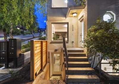The front entrance of a house with steps leading up to the door and a small garden area.