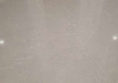 A close-up of a glossy kitchen countertop with light gray veining.