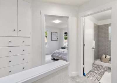 A hallway with built-in cabinets, leading to two bedrooms and a bathroom.