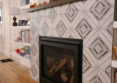Modern fireplace with a unique tile design, featuring autumn decorations on the mantel and a TV mounted above.