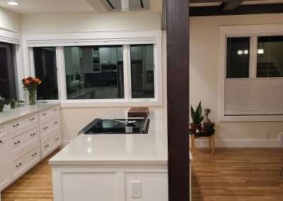 The modern kitchen features a central island, black and white theme, and expansive windows for natural light