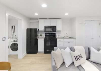 A modern kitchen with black appliances, white cabinets, and an adjacent laundry area with a washer and dryer.