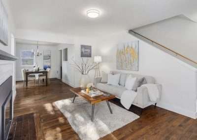 An open living and dining area with a grey couch, wooden coffee table, decorative vase, and a view of the dining room