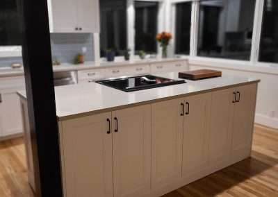 A spacious kitchen island featuring ample storage with white cabinets and black handles, situated in a modern kitchen with hardwood floors.