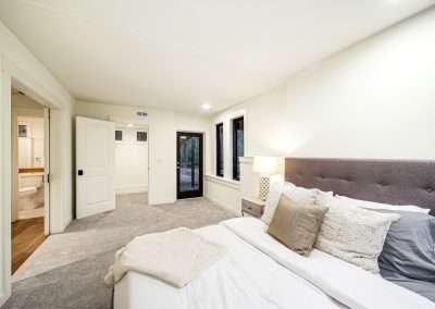 A spacious master bedroom with a plush bed, bedside lamps, and an ensuite bathroom, featuring soft carpeting and a modern design.