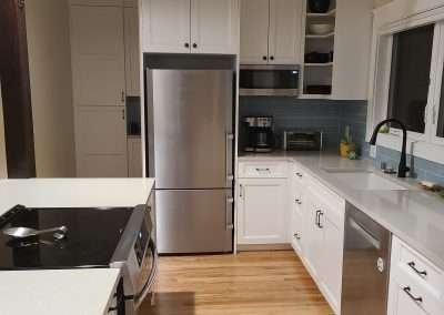 A sleek, modern kitchen featuring stainless steel appliances, white cabinets, and hardwood floors.