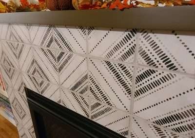 Stylish fireplace decorated for the fall season, with patterned tiles, pumpkins, and autumn leaves on the mantel.