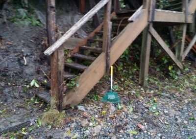 Uneven soil with tools lying near a house foundation.