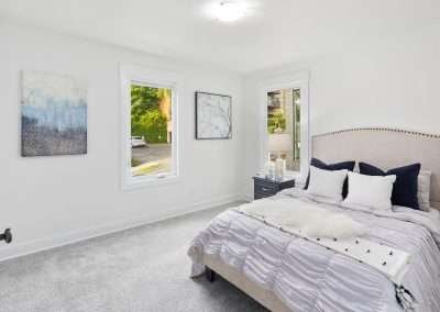 A newly updated bedroom with a cozy bed, modern decor, and large windows letting in natural light