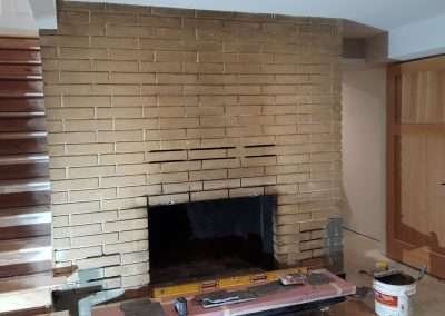 Brick fireplace before renovation with tools and materials.