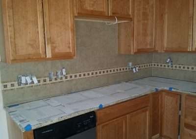 Kitchen backsplash installation with brown mosaic tile border.