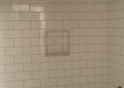 A bathroom with white subway tile walls, a bathtub, and a shower with a handheld showerhead.