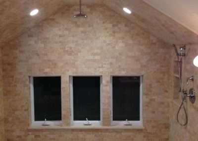 A luxurious bathroom with a spacious shower featuring a pebble floor, multiple showerheads, and large windows.