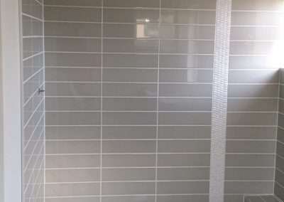Grey rectangular tiles with a vertical white accent strip in a modern shower.