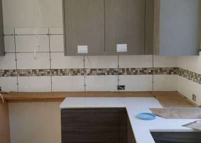Kitchen renovation progress showing white subway tile backsplash with mosaic border.