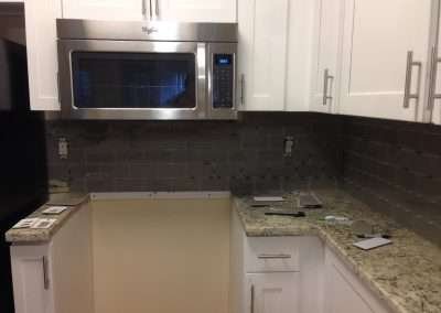Kitchen backsplash installation with brown mosaic tile border.
