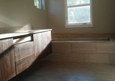 Bathroom renovation in progress featuring a wooden vanity, tiled bathtub platform, and large window.