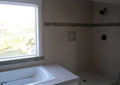 Modern bathroom featuring a freestanding bathtub, a walk-in shower with stone tile accents, and a large window.