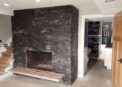Black stone fireplace with a clean, modern design and light-colored hearth.