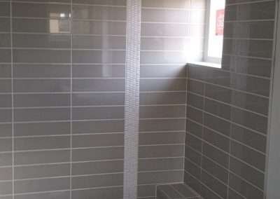 Grey rectangular tiles with a vertical white accent strip in a modern shower.