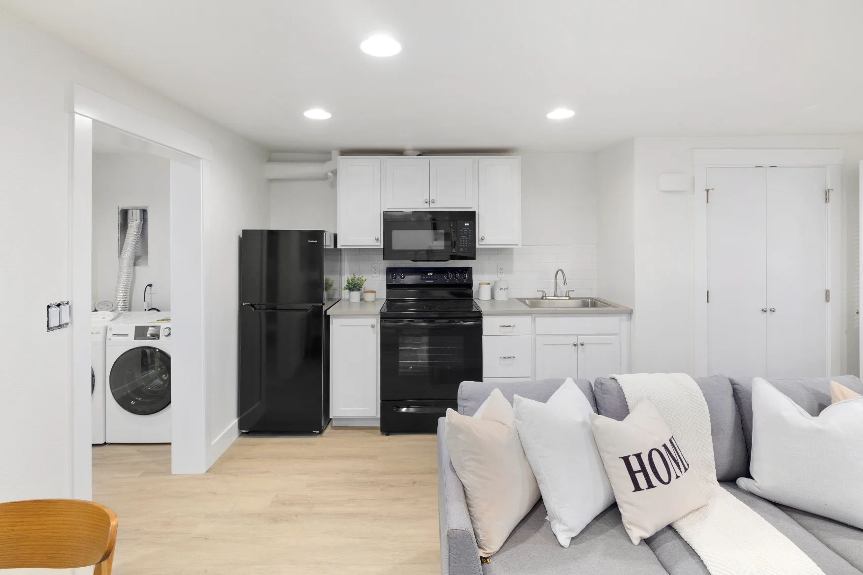 A modern open-plan living area with a cozy sofa, fireplace, dining table, and kitchen in the background.