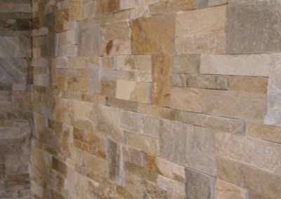 A close-up of a wall covered in beige and brown natural stone tiles.