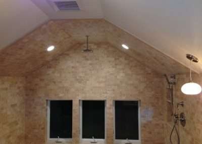 A luxurious bathroom with a vaulted ceiling, stone walls, and a large shower area with multiple showerheads.