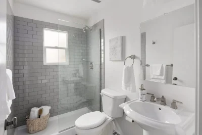 Luxurious modern bathroom featuring a freestanding white bathtub, glass walk-in shower, and textured white walls.