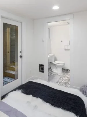 A bedroom with a cozy bed and direct access to a bathroom with patterned tiles.