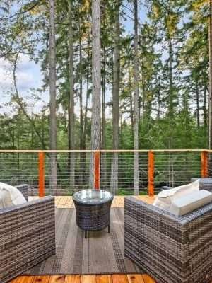 A wooden deck with outdoor seating, surrounded by tall trees and forest views.