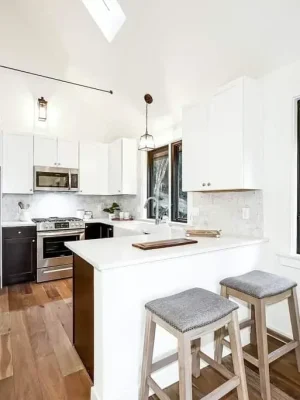 Bright modern kitchen with white cabinetry, a central island with bar stools, and stainless steel appliances.